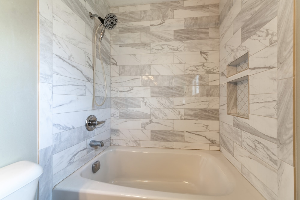 Modern bathroom interior with alcove bathtub with marble tiles surround - Big Easy Bathrooms