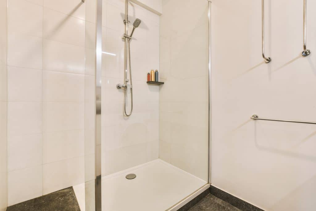 Stylish bathroom interior design with glass shower with shelf in modern apartment