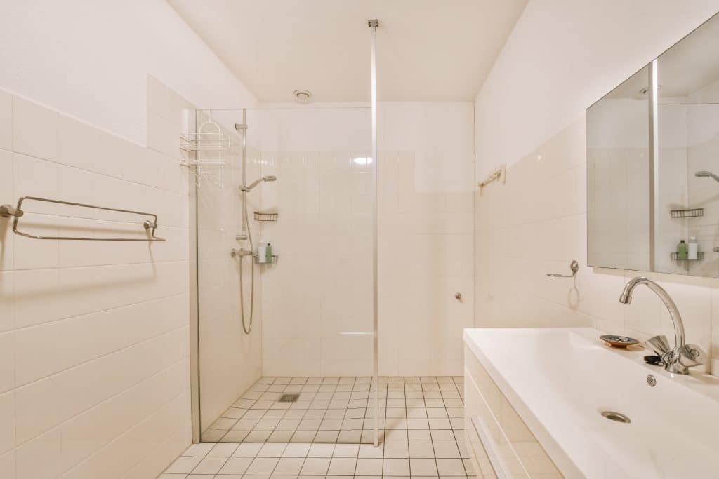 Sinks with mirrors and shower box with glass door in modern bathroom with white tiled walls