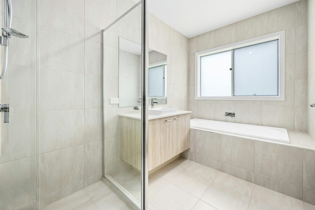 Bathroom with a window beside a frameless glass shower and a built-in bathtub