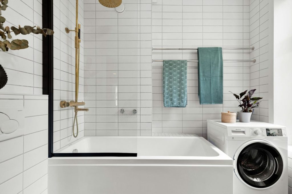 Bathtub with a half glass screen, a brass handheld shower and towel bars