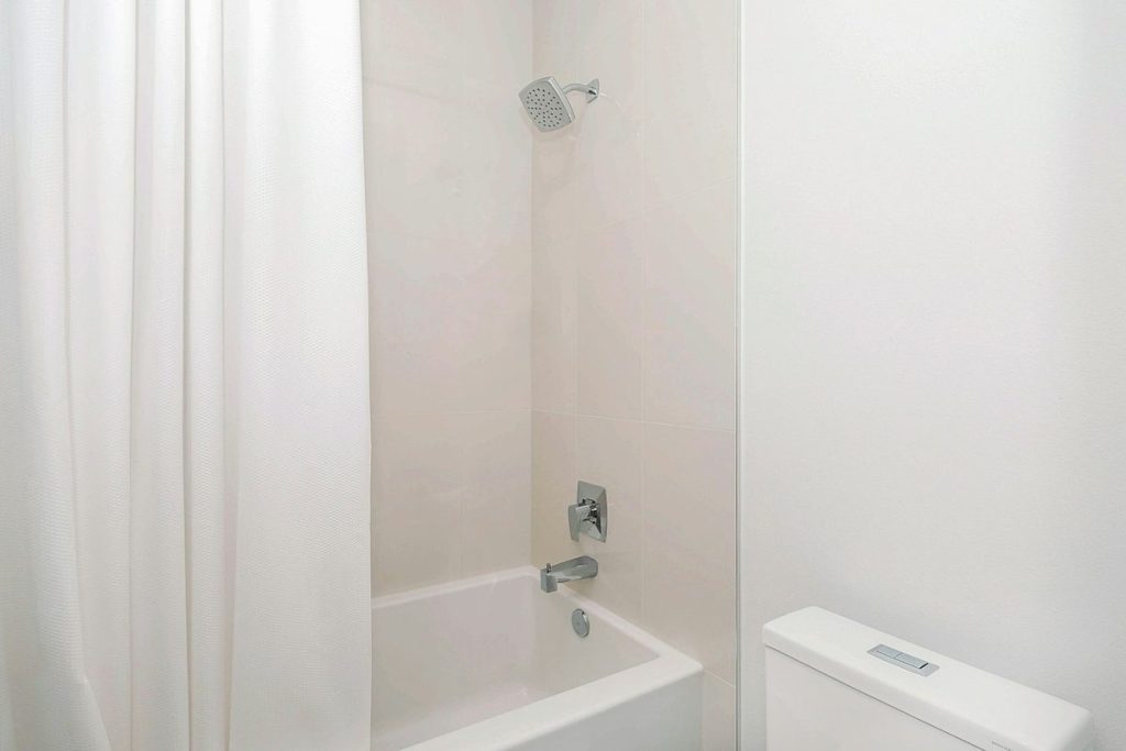 Bathtub with a shower curtain and a tall tub wall to step over