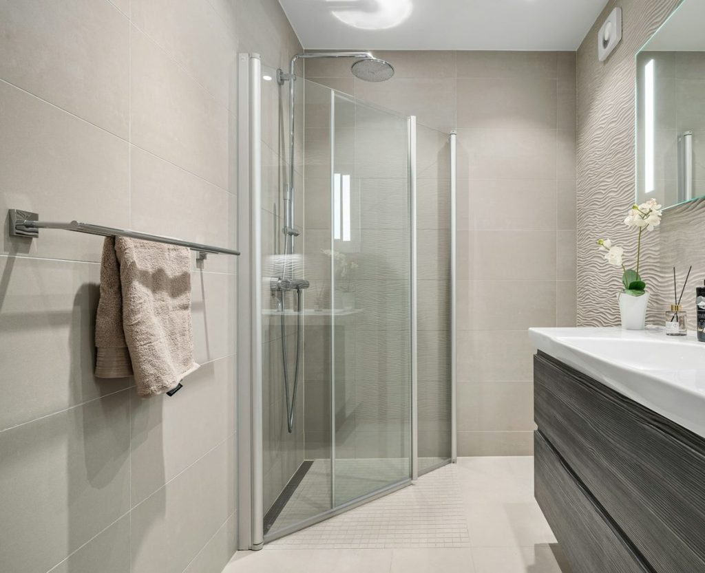 Corner shower with glass doors and a linear drain at the entry