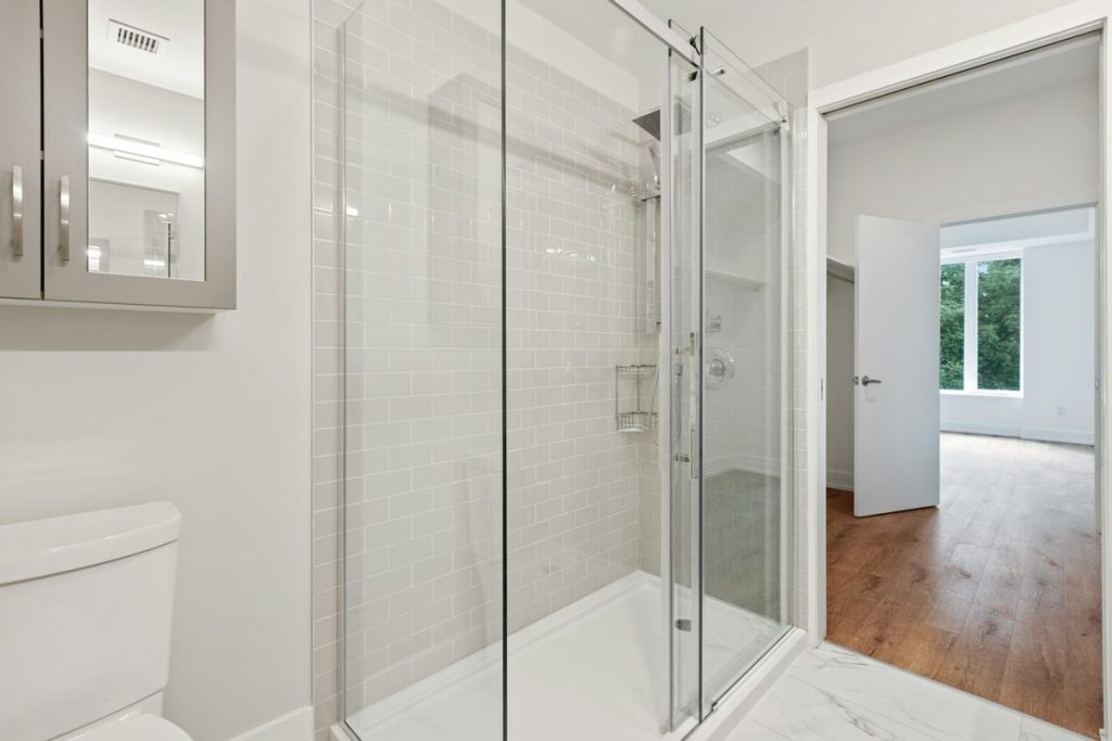 Low-threshold shower with sliding glass doors and light tile walls