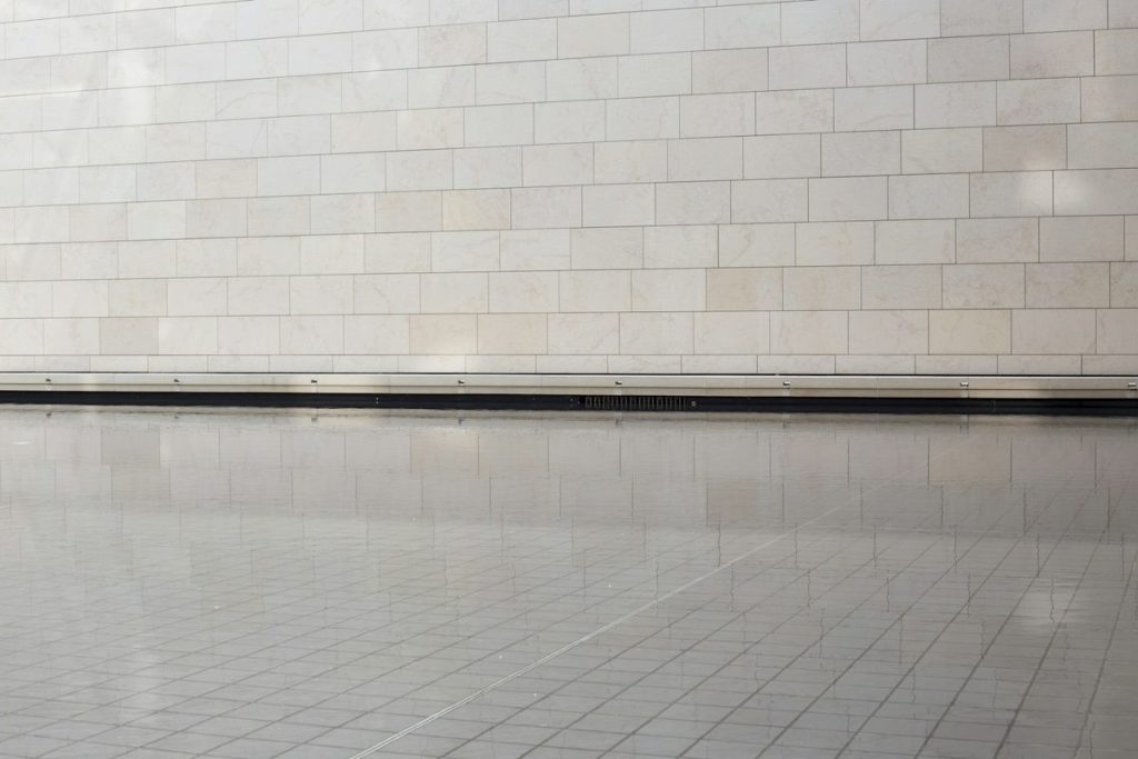 Linear drain running along the wall of a tiled shower floor