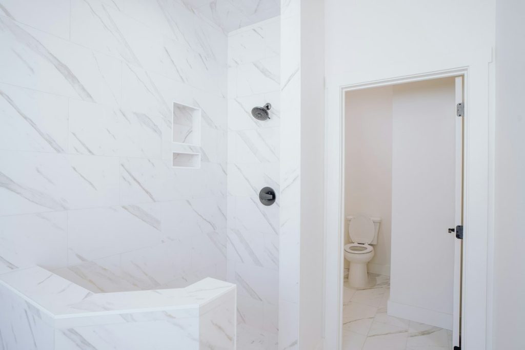 Marble-look walk-in shower with a built-in corner bench and a recessed niche