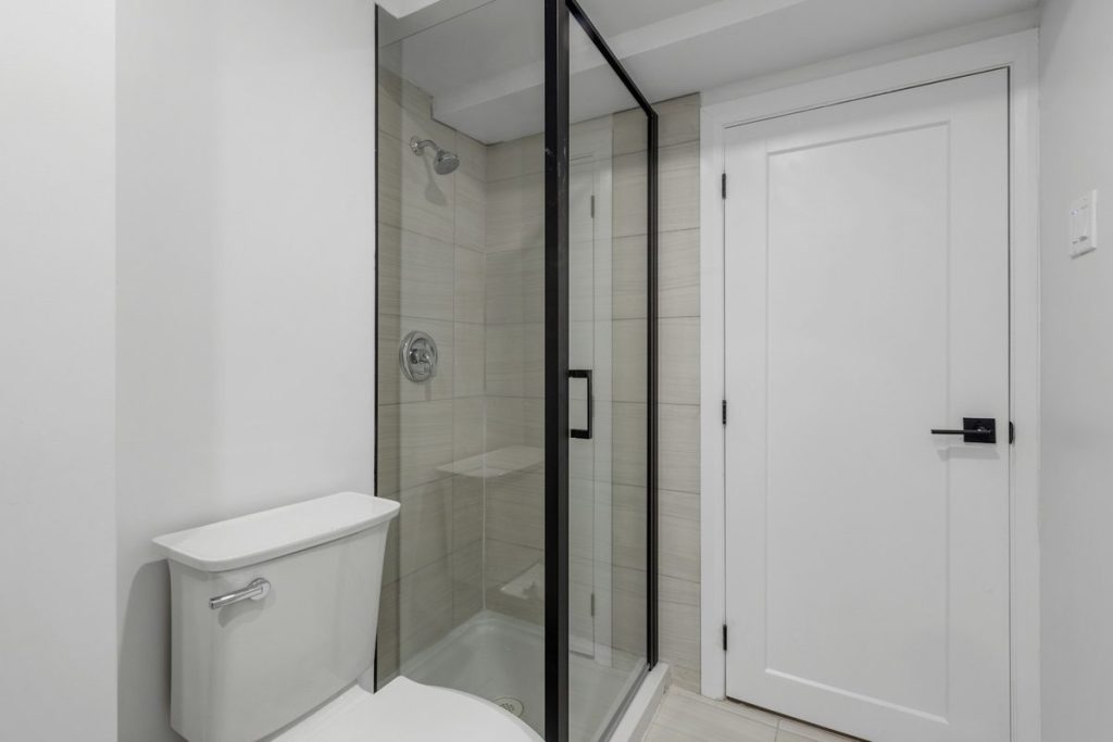 Walk-in shower with a low curb and a black-framed glass door